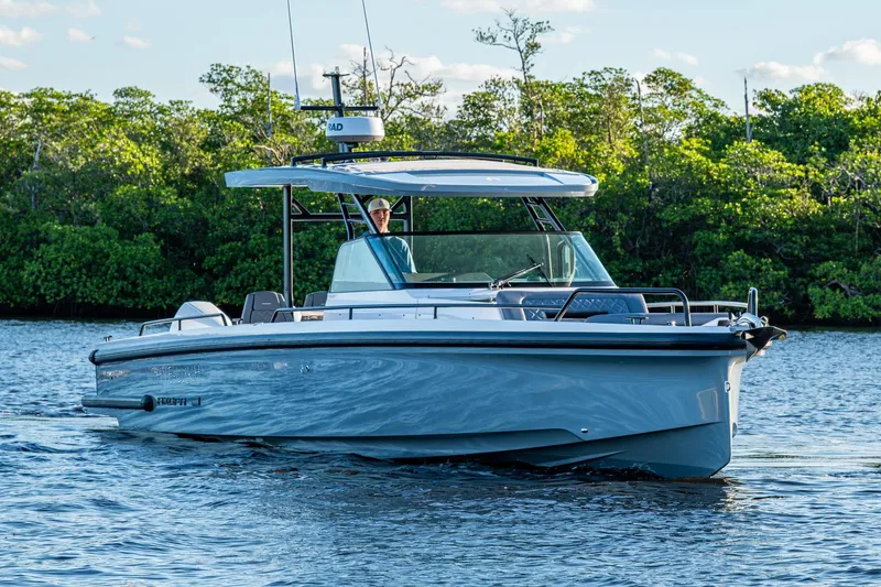 Slide: The Image of 2021 Axopar 37 boat cruising on a calm river with lush greenery in the background. - 47