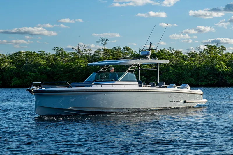 Slide: The Image of 2021 Axopar 37 boat cruising on a serene lake with lush greenery. - 49