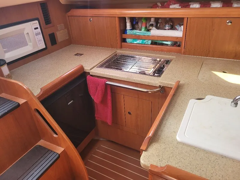 Slide: The Image of 2008 Hunter 33 yacht kitchen with wooden cabinetry, sink, and microwave. - 16