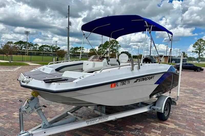 Slide: The Image of 2023 Starcraft SVX 171 OB boat on trailer with blue canopy, parked outdoors. - 1