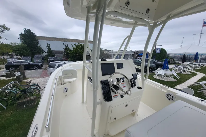 Slide: The Image of 2025 Cobia 220 Center Console boat with modern helm, parked outdoors. - 11