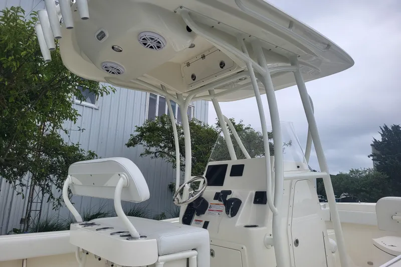 Slide: The Image of 2025 Cobia 220 Center Console boat with T-top and modern helm controls. - 2