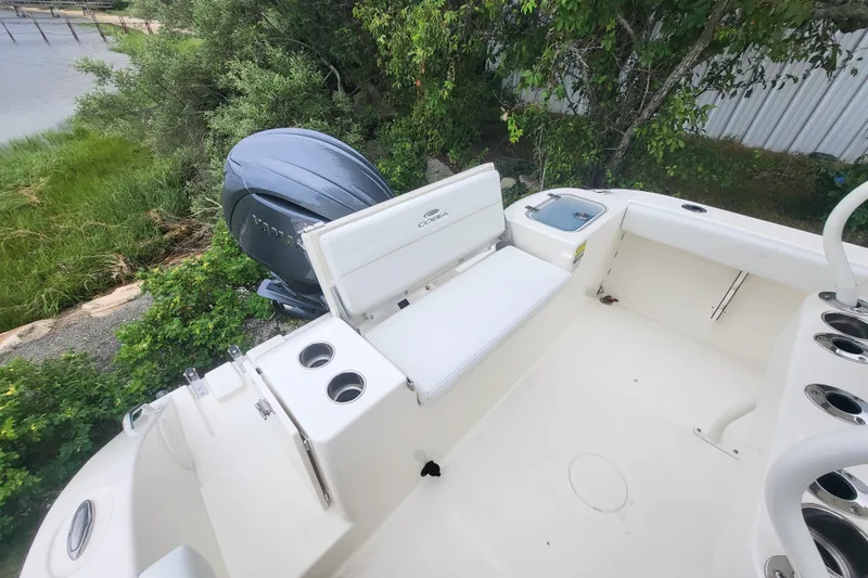 Slide: The Image of 2025 Cobia 220 Center Console boat with Yamaha engine, docked near lush greenery. - 8