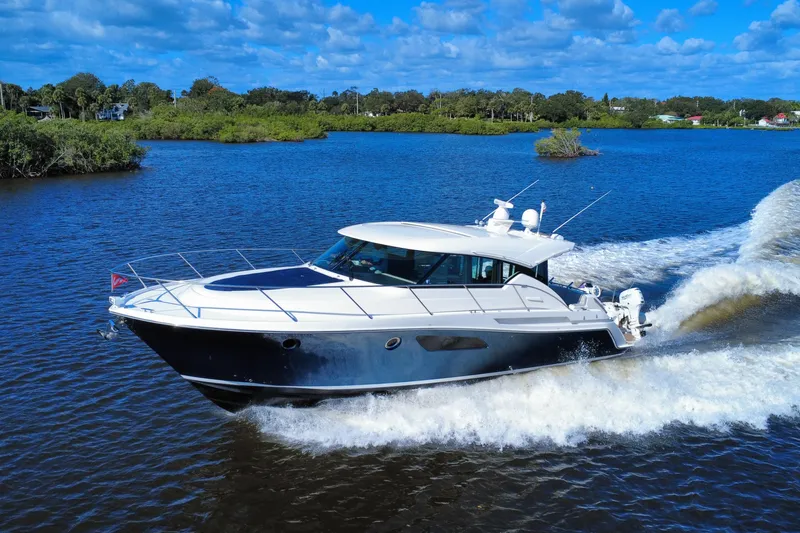 The Image of 2016 Tiara Yachts C44 Coupe cruising on a scenic blue waterway. - 0