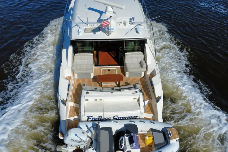 Slide: The Image of 2016 Tiara Yachts C44 Coupe cruising with tender, rear view on water. - 13