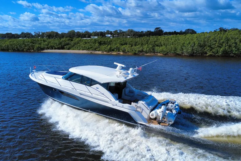Slide: The Image of 2016 Tiara Yachts C44 Coupe cruising on a scenic river under a blue sky. - 3