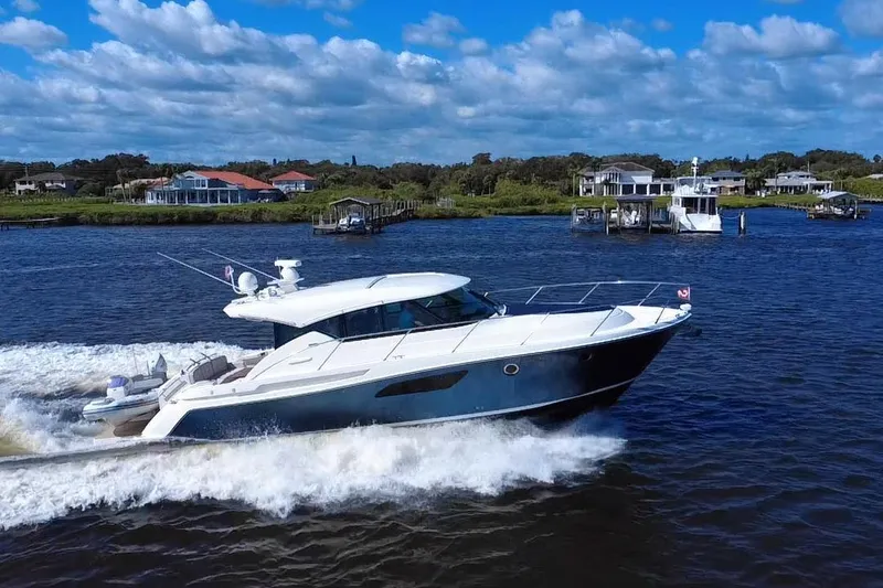 Slide: The Image of 2016 Tiara Yachts C44 Coupe cruising on a scenic waterway under a blue sky. - 4