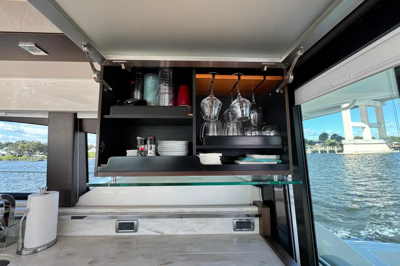 Slide: The Image of Interior of 2016 Tiara Yachts C44 Coupe with open cabinet and glassware, overlooking water. - 42