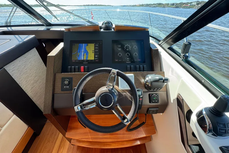 Slide: The Image of 2016 Tiara Yachts C44 Coupe helm with navigation screens and steering wheel. - 45