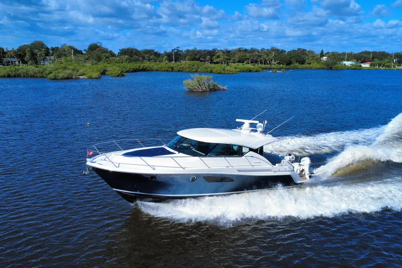 Slide: The Image of 2016 Tiara Yachts C44 Coupe cruising on a scenic blue lake under a clear sky. - 5