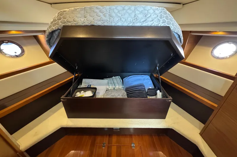Slide: The Image of 2016 Tiara Yachts C44 Coupe cabin with under-bed storage, featuring neatly organized linens. - 52