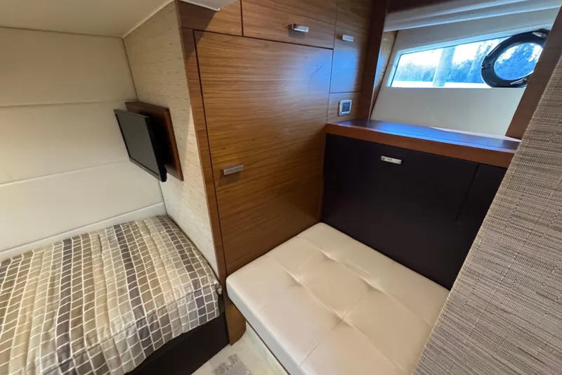 Slide: The Image of 2016 Tiara Yachts C44 Coupe interior with bed, TV, and wooden cabinetry. - 60