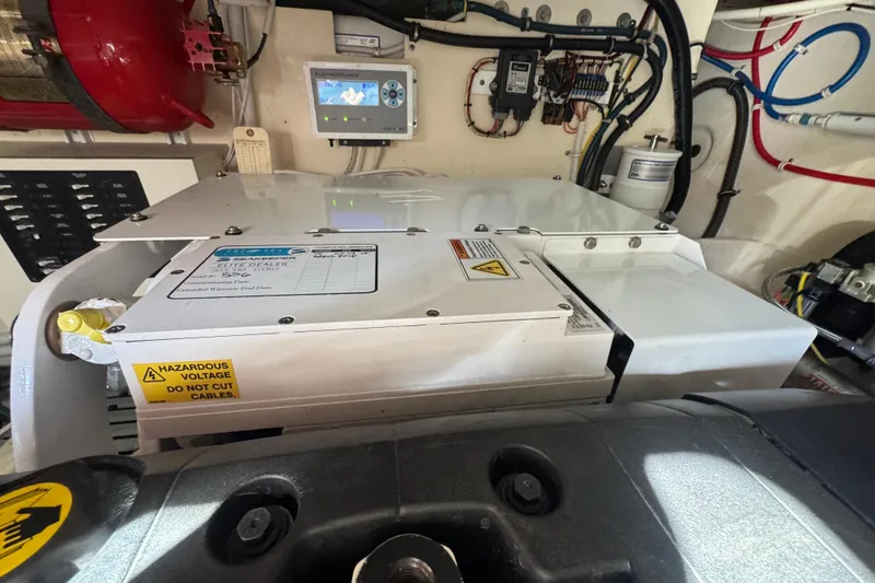 Slide: The Image of Engine room of 2016 Tiara Yachts C44 Coupe with electrical components and warning labels. - 81