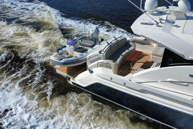 Slide: The Image of 2016 Tiara Yachts C44 Coupe cruising with a small boat on the water. - 9