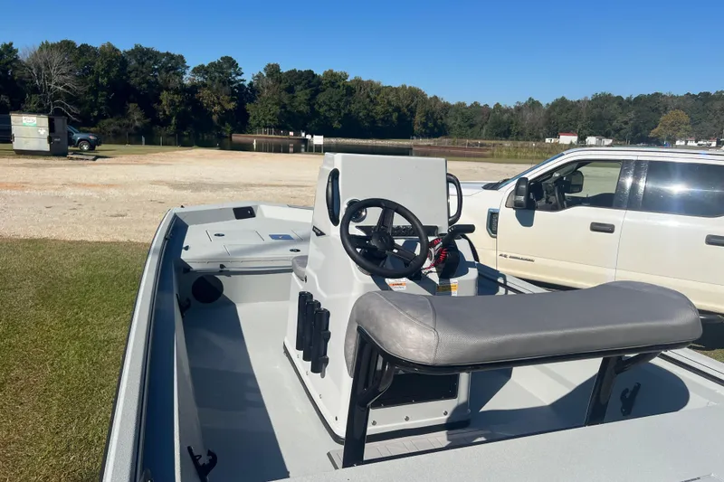 Slide: The Image of 2026 Avid 18 Rogue CC boat interior with steering wheel, parked near white vehicle. - 12