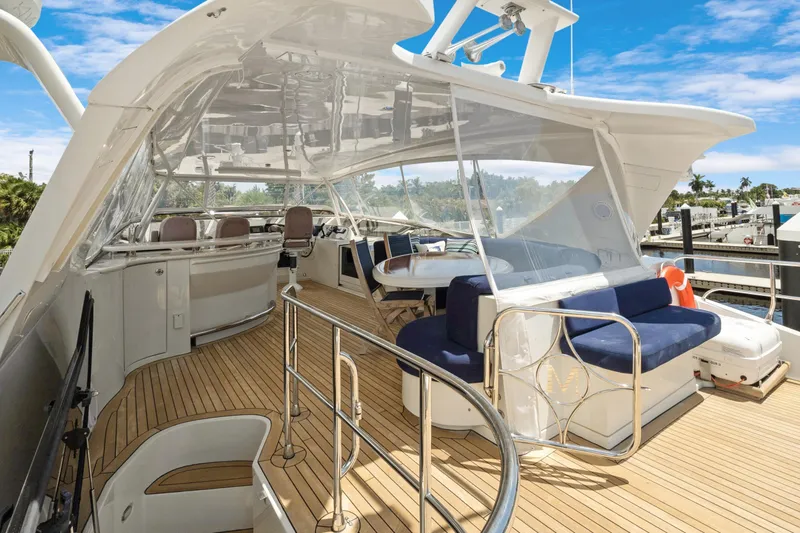 Slide: The Image of Luxurious 2008 Marquis 690 yacht deck with seating, helm, and clear canopy under blue sky. - 44