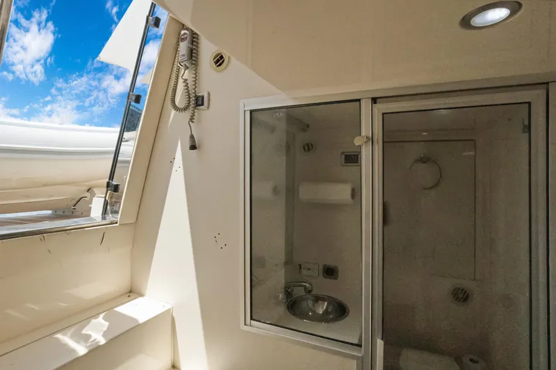 Slide: The Image of 2008 Marquis 690 yacht bathroom with shower, sink, and open window under blue sky. - 55