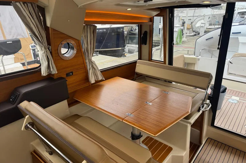 Slide: The Image of 2024 Ranger Tugs R-29 S interior with leather seating and marina view. - 15