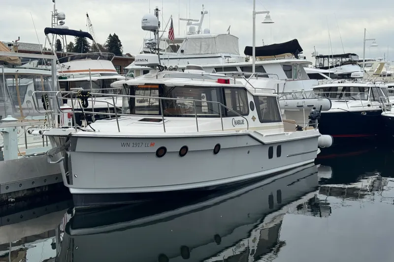Slide: The Image of 2024 Ranger Tugs R-29 S docked at marina, reflecting on calm water. - 25