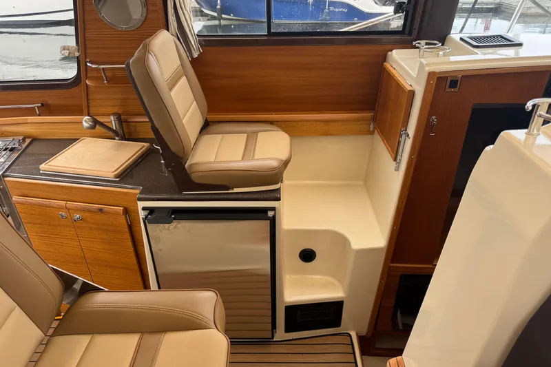Slide: The Image of 2024 Ranger Tugs R-29 S interior with Garmin navigation, wood accents, and cozy seating. - 6