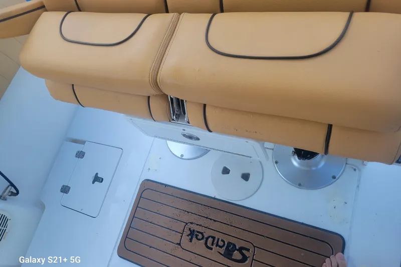 Slide: The Image of Interior of a 2005 Intrepid 323 Cuddy boat with tan seating and deck mat. - 23