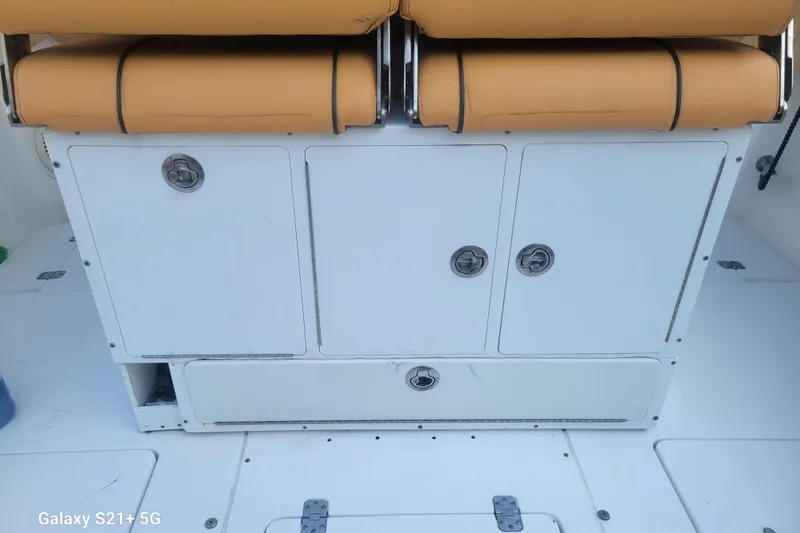 Slide: The Image of 2005 Intrepid 323 Cuddy boat interior with storage compartments and tan seating. - 27
