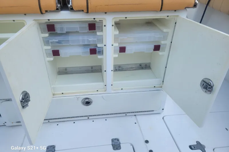 Slide: The Image of Open storage compartment on a 2005 Intrepid 323 Cuddy boat with tackle boxes inside. - 28