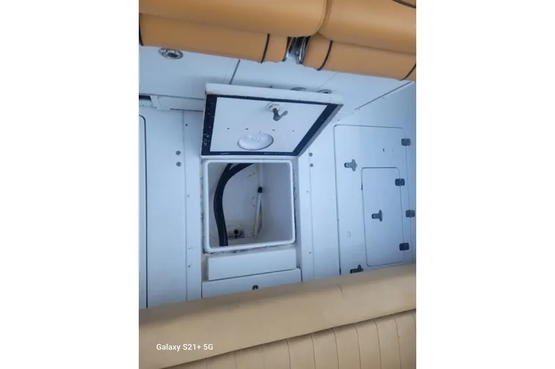 Slide: The Image of 2005 Intrepid 323 Cuddy interior storage compartments with tan seating. - 29