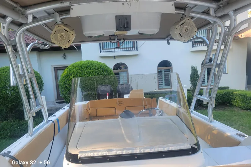 Slide: The Image of 2005 Intrepid 323 Cuddy boat with seating, speakers, and windshield, parked near a house. - 30