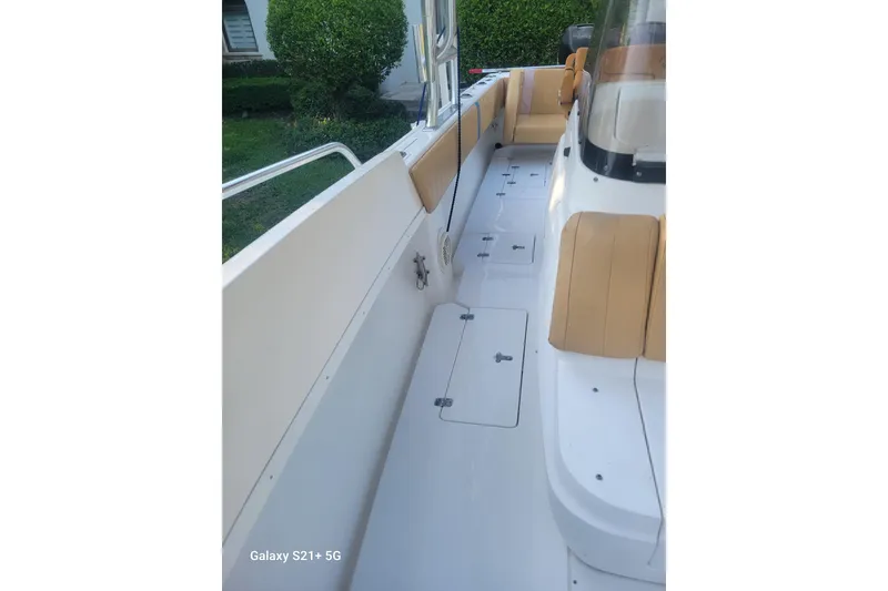 Slide: The Image of 2005 Intrepid 323 Cuddy boat interior with beige seating and storage compartments. - 32