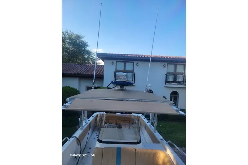 Slide: The Image of 2005 Intrepid 323 Cuddy boat with antennas, parked near a house with a tiled roof. - 34