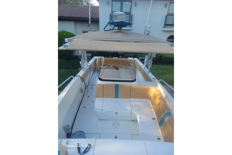 Slide: The Image of 2005 Intrepid 323 Cuddy boat with spacious seating and canopy, docked near a house. - 35