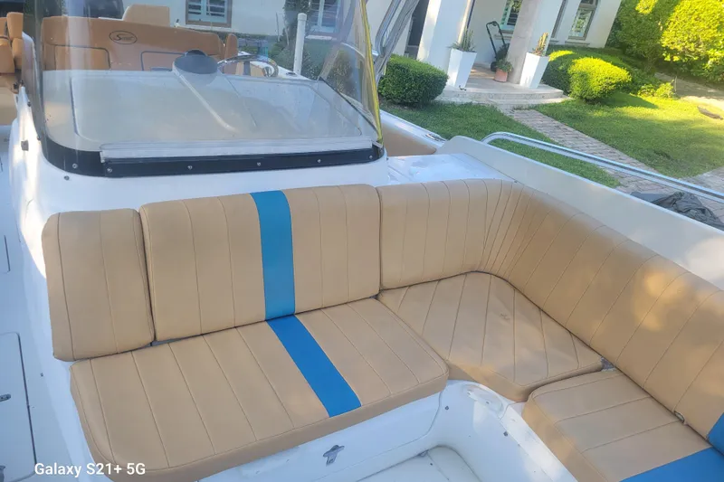 Slide: The Image of 2005 Intrepid 323 Cuddy boat with tan and blue seating, docked near a garden. - 37