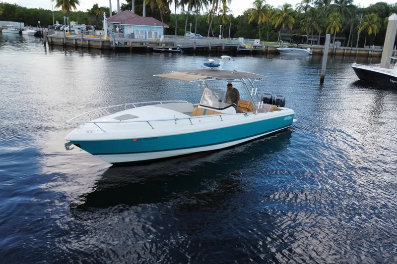 Slide: The Image of 2005 Intrepid 323 Cuddy boat on calm water near a dock with palm trees. - 4