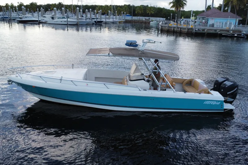 Slide: The Image of 2005 Intrepid 323 Cuddy boat on calm water near a marina. - 5