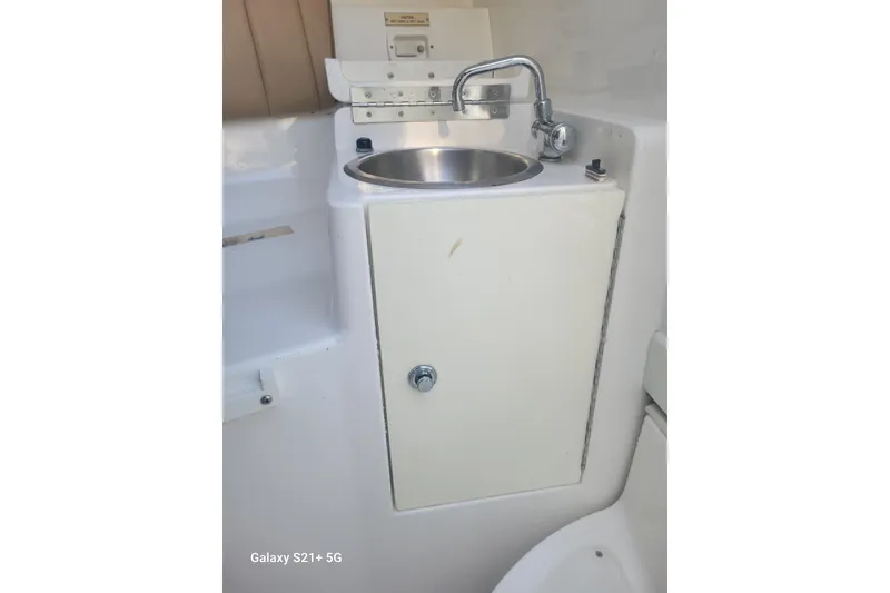 Slide: The Image of 2005 Intrepid 323 Cuddy boat sink with faucet and storage cabinet. - 56