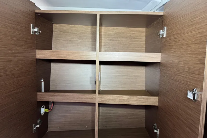 Slide: The Image of Empty wooden cabinet inside 2022 Beneteau Oceanis 46.1 yacht, featuring multiple shelves. - 32