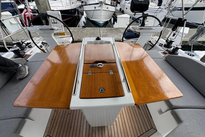 Slide: The Image of Cockpit of 2022 Beneteau Oceanis 46.1 yacht with wooden table and dual steering wheels. - 45