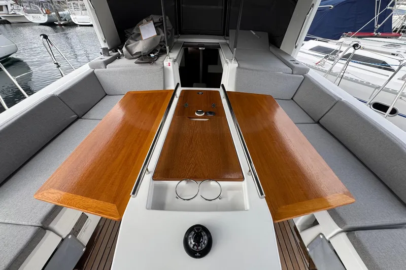 Slide: The Image of Beneteau Oceanis 46.1 yacht cockpit with wooden table and gray seating, 2022 model. - 46