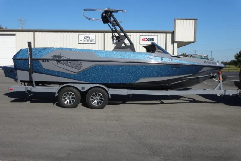 The Image of 2022 Axis T23 boat on trailer, blue and gray, parked outside dealership. - 1