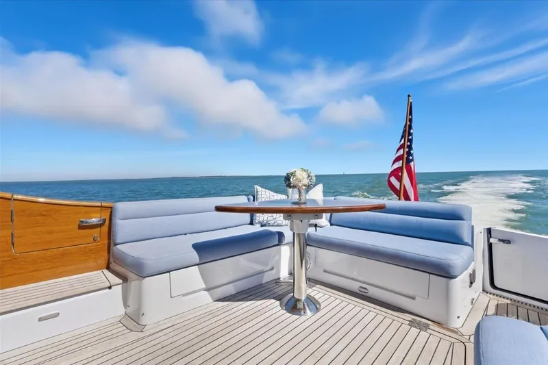 Slide: The Image of 2015 Hinckley Talaria 43 yacht deck with seating, table, and American flag on open sea. - 6