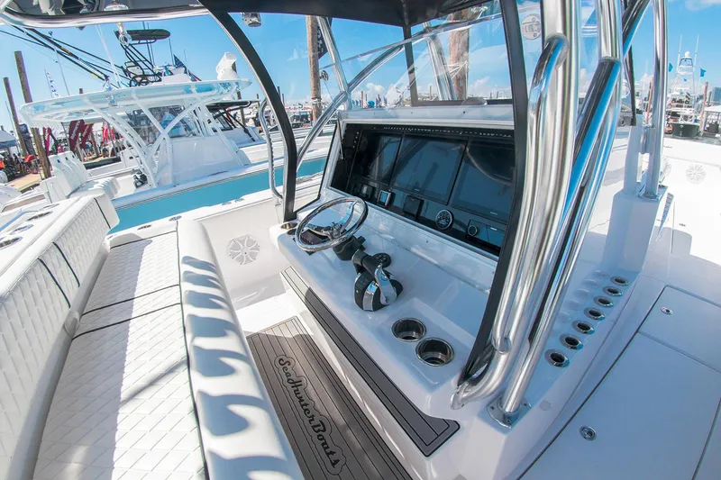Slide: The Image of 2021 SeaHunter 41 CTS boat interior with luxurious seating and modern controls, docked by the water. - 10