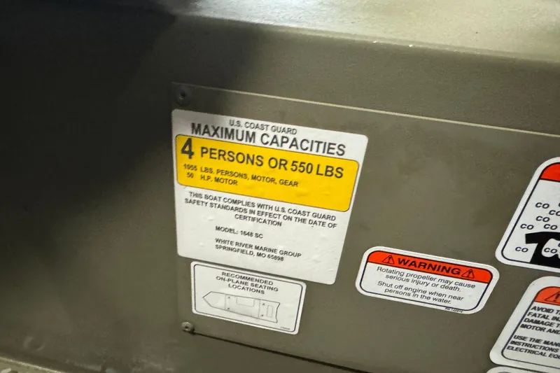 Slide: The Image of 2024 Tracker Grizzly 1648 SC capacity label: 4 persons or 550 lbs, safety warnings included. - 7