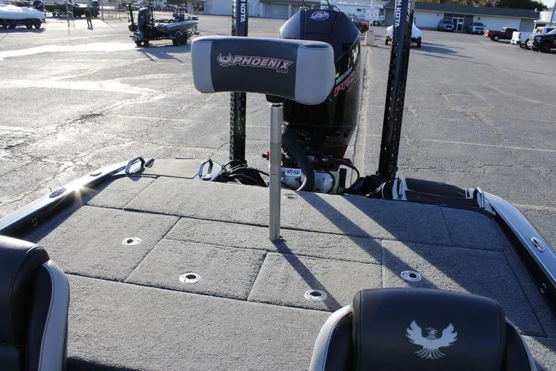 Slide: The Image of 2025 Phoenix 921 ELITE boat interior with motor and seating, parked outdoors. - 27