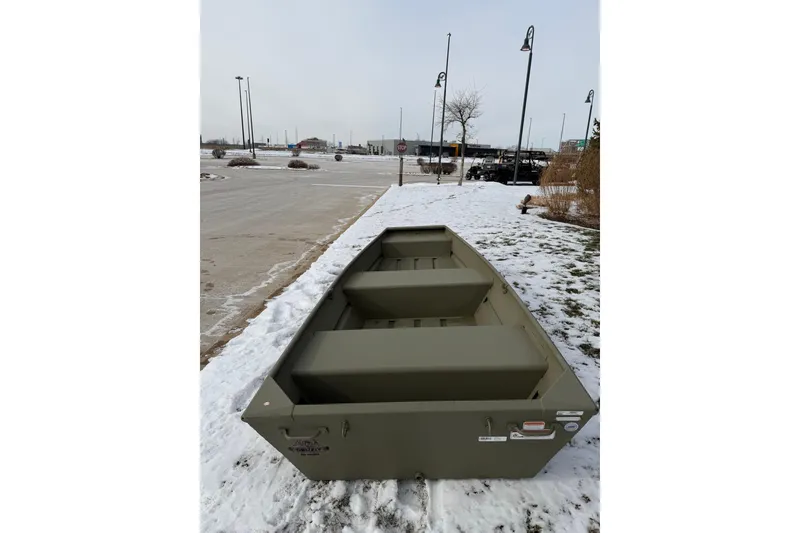 Slide: The Image of 2026 Tracker Grizzly 12 Jon boat on snowy ground, showcasing its sturdy design. - 2