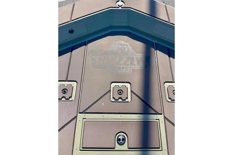 Slide: The Image of 2026 Tracker Grizzly 2072 CC boat deck with storage compartments and logo. - 45