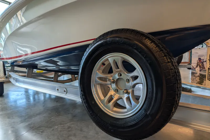 Slide: The Image of 2026 Mako 18 Pro Skiff Patriot Edition on trailer, showcasing tire and hull details. - 7