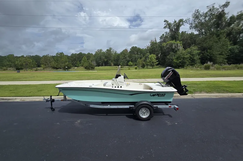 The Image of 2026 Mako Pro Skiff 15 CC boat on trailer, parked on a road with greenery background. - 0