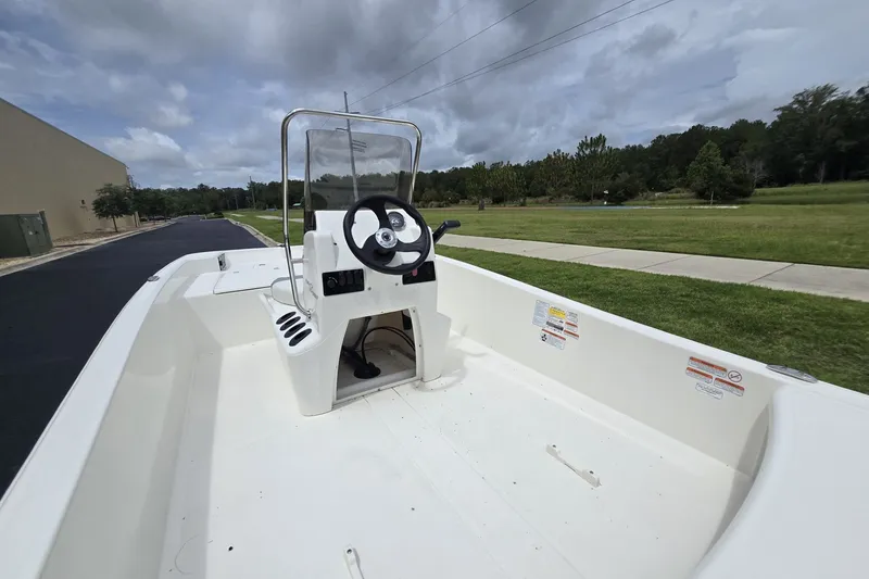 Slide: The Image of 2026 Mako Pro Skiff 15 CC boat with center console on a grassy landscape. - 2