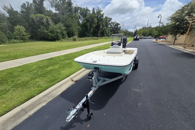 Slide: The Image of 2026 Mako Pro Skiff 15 CC boat on trailer, parked on a suburban street. - 4